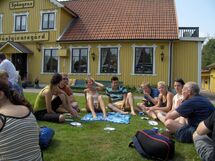 People sitting in the grass outside a building. Photo. 