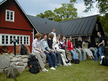 People sitting on a stone wall outside a house. Photo. 